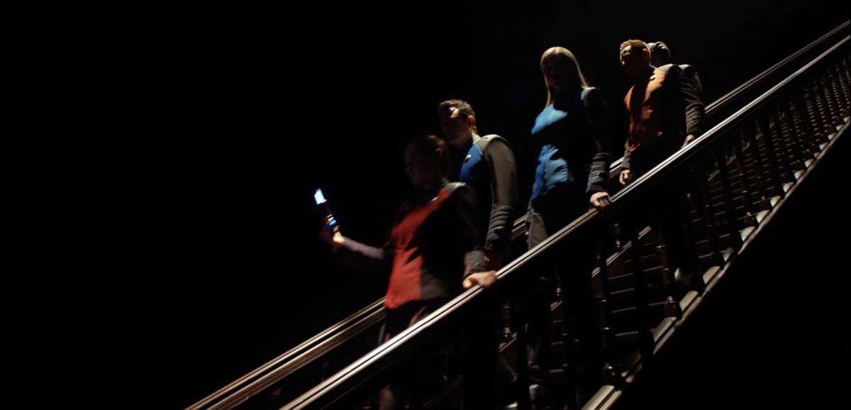 The crew descends down the dark staircase
